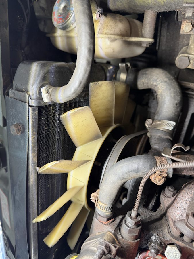 Close view of the coolant vessel, radiator, pale fan and hoses