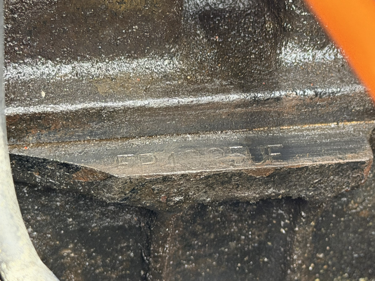 Worn stamped engine-number flange with FP at the left and UE at the right