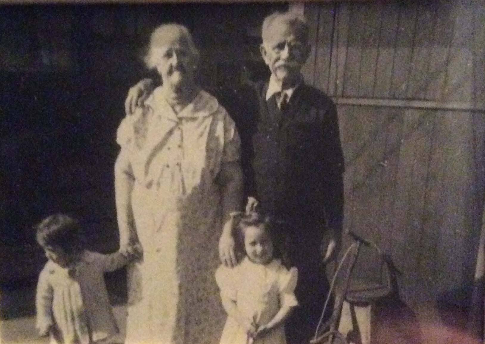 An elderly couple outdoors with two small children, identified within the family as Dennis C. Leahey